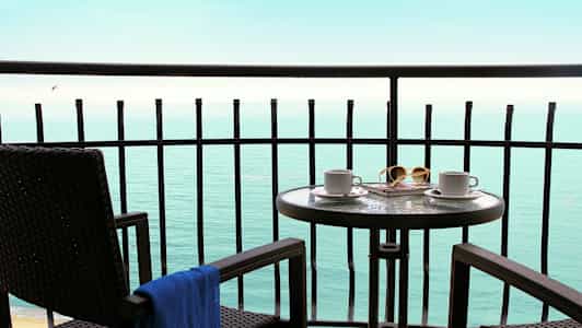 Parveke, jossa pöytä ja tuolit, näkymä merelle. (Tekoälyn luoma teksti)