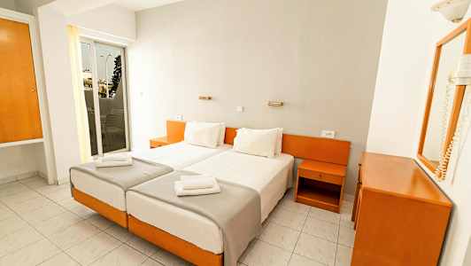 Kaksi yhden hengen vuodetta valkoisilla vuodevaatteilla hotellihuoneessa, jossa on valkoista ja puunsävyistä sisustusta. (Tekoälyn luoma teksti)