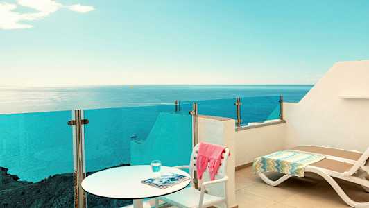 Terassi, jossa on tuoleja ja lasikaide, merinäköala. (Tekoälyn luoma teksti)