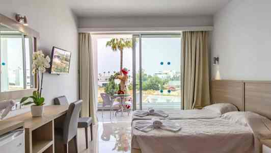 Hotellihuone, jossa kaksi erillistä vuodetta, työpöytä ja parveke istuimineen. (Tekoälyn luoma teksti)