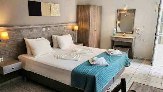 Hotellihuone, jossa on parivuode, vaatekaappi, meikkipöytä ja vaaleat tekstiilit. (Tekoälyn luoma teksti)