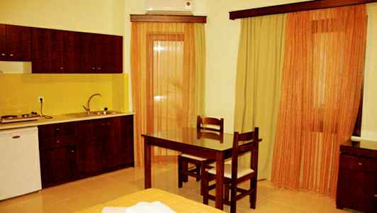 Huone, jossa keittiö, pöytä ja kaksi tuolia sekä verhot ikkunoissa. (Tekoälyn luoma teksti)