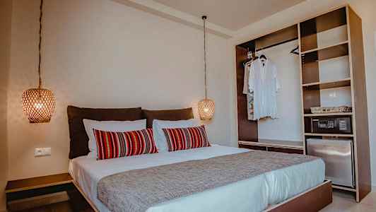 Makuuhuone, jossa parivuode, punaisia koristeellisia tyynyjä ja avoin vaatekaappi. (Tekoälyn luoma teksti)