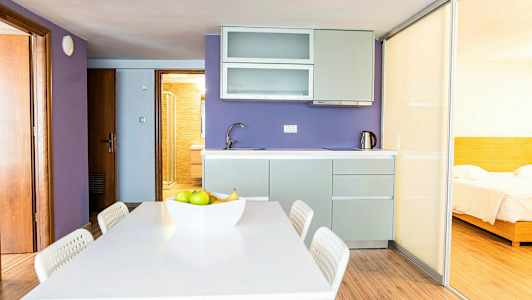 Keittiö, jossa on violetit seinät, ruokailutila ja liukuovi, joka johtaa makuuhuoneeseen. (Tekoälyn luoma teksti)