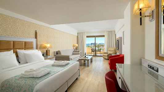 Hotellihuone, jossa on sänky, istuma-alue ja parveke näköalalla. (Tekoälyn luoma teksti)