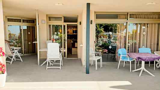 Kuva kahdesta terassista, joissa istuinpaikkoja lasiovien edessä, jotka johtavat huoneistoihin. (Tekoälyn luoma teksti)