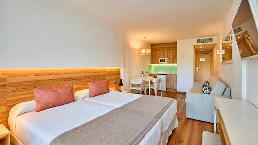 Hotellihuoneen sisustus, jossa on parivuode, keittiöalue ja oleskelutila. (Tekoälyn luoma teksti)