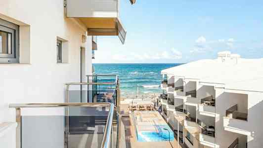 Näkymä parvekkeelta merelle hotellirakennusten ja uima-altaan kanssa. (Tekoälyn luoma teksti)