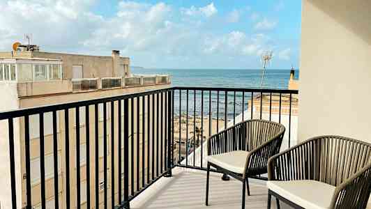 Parveke, jossa on kaksi tuolia ja näkymä merelle. (Tekoälyn luoma teksti)