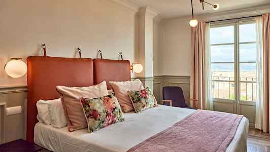 Hotellihuone, jossa on sänky, koristeellisia tyynyjä ja ikkuna näkymällä. (Tekoälyn luoma teksti)