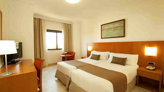 Hotellihuone, jossa on kaksi yhden hengen sänkyä ja puupaneeliseinä. (Tekoälyn luoma teksti)