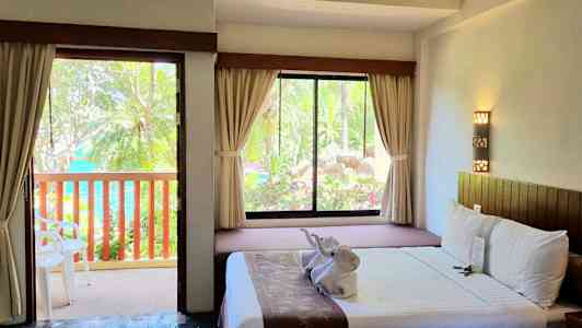 Hotellihuone, josta on avoin ovi parvekkeelle, ja sänky, jossa on koristeita. (Tekoälyn luoma teksti)