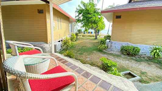 Kaksi tuolia, joissa on punaiset tyynyt, terassilla näköalalla puutarhaan ja mereen. (Tekoälyn luoma teksti)