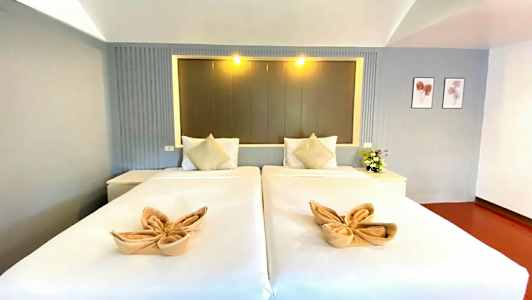 Kaksi yhden hengen vuodetta, joissa on koristeltuja pyyhkeitä ja tyynyjä, tyylikkäässä huoneessa. (Tekoälyn luoma teksti)