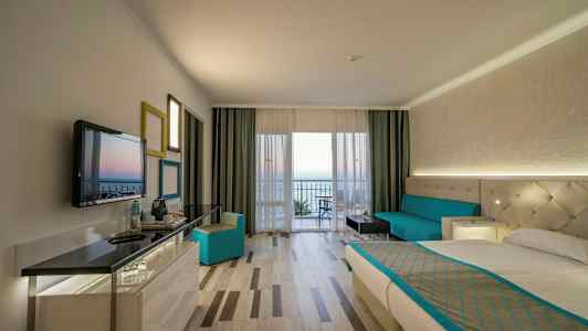 Hotellihuoneen sisätila, jossa on sänky, sohva ja näkymä parvekkeelle. (Tekoälyn luoma teksti)