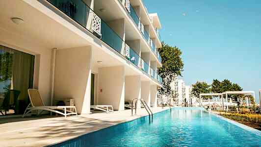 Hotellirakennus, jossa parvekkeet ja uima-allasalue. (Tekoälyn luoma teksti)