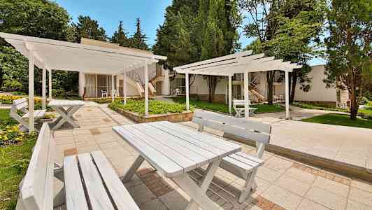 Valkoisiksi maalattuja ulkokalusteita vehreyden ympäröimänä. (Tekoälyn luoma teksti)