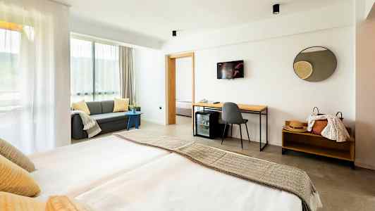 Moderni hotellihuone, jossa on parivuode, sohva ja työpöytä. (Tekoälyn luoma teksti)