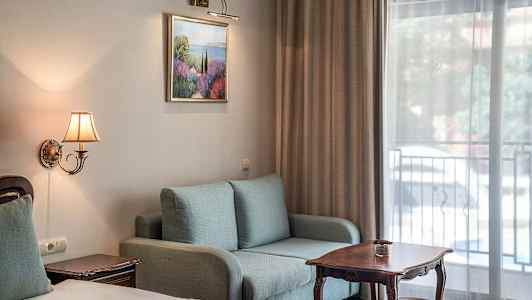 Hotellihuoneen sisustus, jossa sohva, pöytä ja sänky. (Tekoälyn luoma teksti)