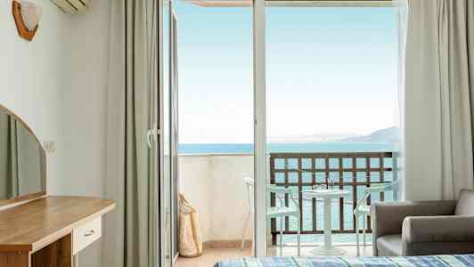Hotellihuone, jossa avoin parvekeovi ja merinäköala. (Tekoälyn luoma teksti)