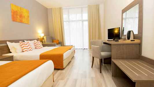 Hotellihuone, jossa on kaksi sänkyä, työpiste ja istuinpaikkoja. (Tekoälyn luoma teksti)