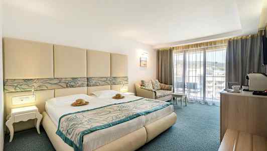 Hotellihuone, jossa parivuode, sohva ja parveke. (Tekoälyn luoma teksti)