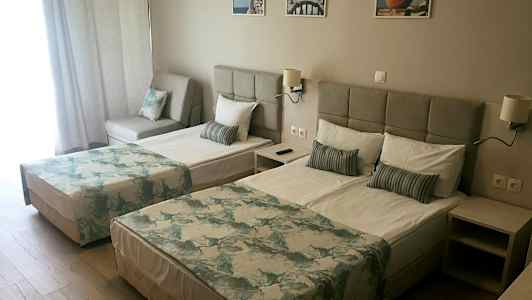 Kahden hengen huone, jossa kaksi vuodetta, sohva ja vaalea sisustus. (Tekoälyn luoma teksti)