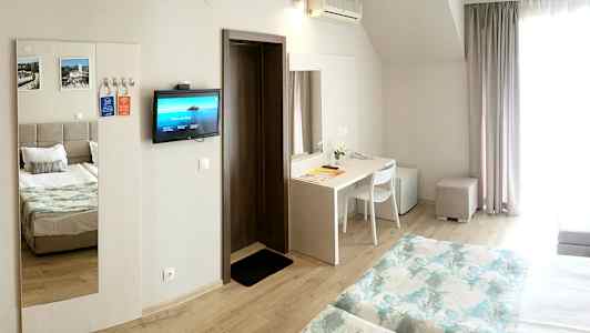 Hotellihuone, jossa kaksi sänkyä, työpöytä, jääkaappi ja seinälle kiinnitetty televisio. (Tekoälyn luoma teksti)