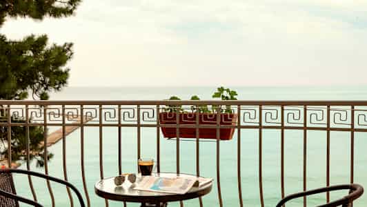 Parveke, jolta avautuu näkymä merelle, pöytä, tuolit ja kukkalaatikko. (Tekoälyn luoma teksti)