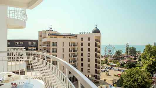 Näkymä parvekkeelta hotellialueelle, jossa on maailmanpyörä ja meri taustalla. (Tekoälyn luoma teksti)