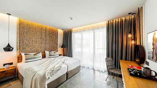 Modernisti sisustettu hotellihuone, jossa parivuode, istuinryhmä ja parveke. (Tekoälyn luoma teksti)