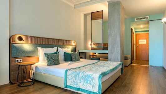 Hotellihuone, jossa on parivuode, puu- ja tekstiilielementtejä, vaaleat seinät ja puusisustus. (Tekoälyn luoma teksti)