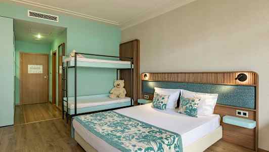 Hotellihuone, jossa on parivuode ja kerrossänky, sisustettu turkoosilla ja beigellä värillä. (Tekoälyn luoma teksti)