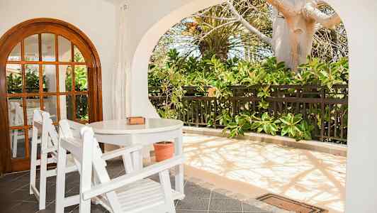 Terassi, jossa on valkoiset puukalusteet ja vehreitä kasveja. (Tekoälyn luoma teksti)