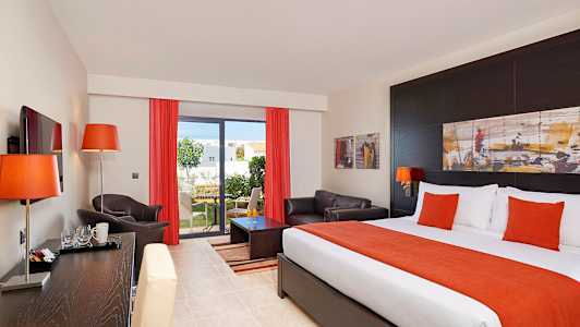 Hotellihuone, jossa sänky, sohva ja näkymä puutarhaan. (Tekoälyn luoma teksti)