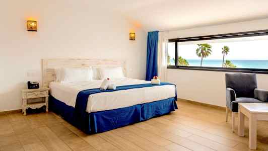 Hotellihuone, jossa on parisänky ja näkymä merelle suuren ikkunan läpi. (Tekoälyn luoma teksti)