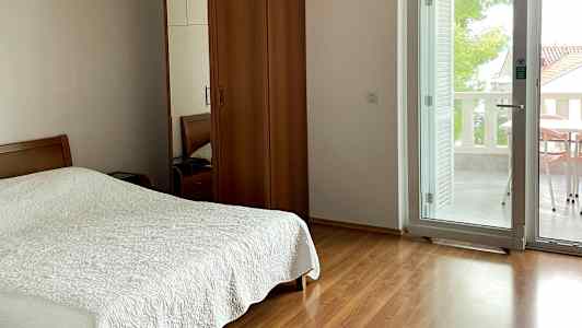 Makuuhuone, jossa parisänky, puinen vaatekaappi ja lasiovi, joka johtaa parvekkeelle. (Tekoälyn luoma teksti)