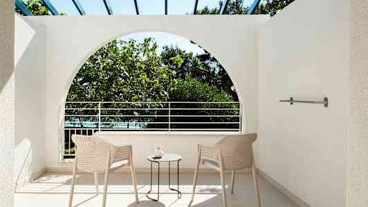 Näkymä terassilta, jossa kaksi tuolia ja pöytä, ulkopuolella olevaan kasvillisuuteen. (Tekoälyn luoma teksti)