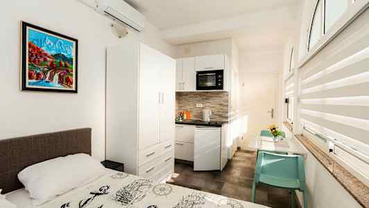 Valoisa huone, jossa on sänky keittokomeron ja ruokapöydän edessä. (Tekoälyn luoma teksti)