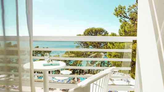 Näkymä parvekkeelta, jossa uima-allas ja meri sekä puita etualalla. (Tekoälyn luoma teksti)