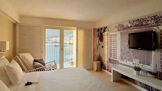 Makuuhuone, josta on näkymä merelle lasiovien kautta, sänky ja seinä koristeellisella valokuvauksella. (Tekoälyn luoma teksti)