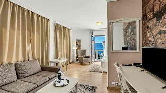 Huone, jossa istuintilat, kirjoituspöytä ja näkymä merelle avoimen oven kautta. (Tekoälyn luoma teksti)