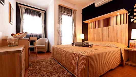 Hotellihuone, jossa on puusisustus, parisänky ja suuret ikkunat. (Tekoälyn luoma teksti)