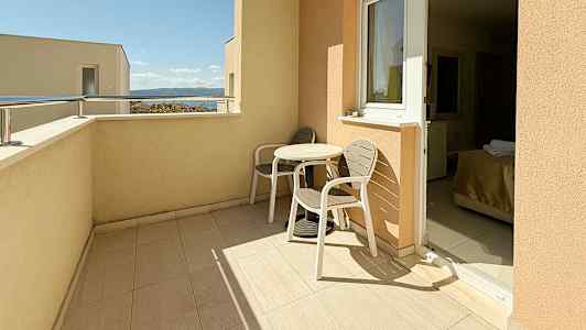 Parveke, jossa kaksi tuolia ja pöytä, näkymä taivaalle ja merelle. (Tekoälyn luoma teksti)