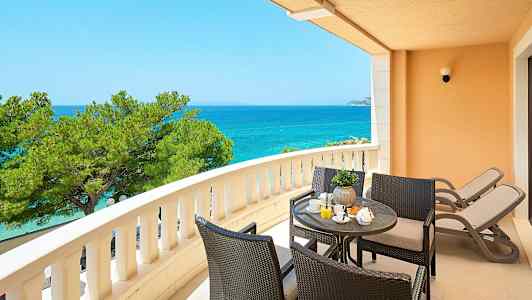 Parveke, jolta on näkymä merelle, istuinryhmä ja kaksi aurinkotuolia. (Tekoälyn luoma teksti)