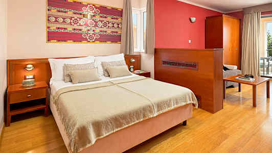 Hotellihuone, jossa on parivuode, yöpöytä ja taidekappale seinällä. (Tekoälyn luoma teksti)