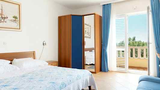 Hotellihuone, jossa on sänky, kaappi peiliovella ja parveke. (Tekoälyn luoma teksti)