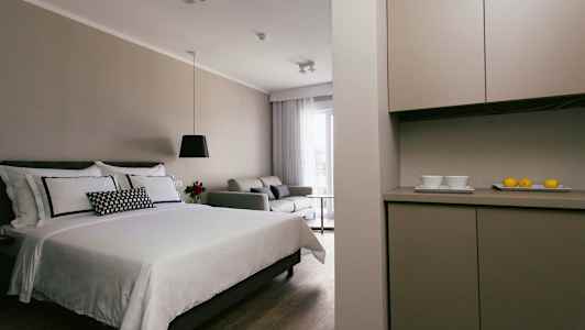 Moderni hotellihuone, jossa sänky, sohva ja keittiöalue. (Tekoälyn luoma teksti)