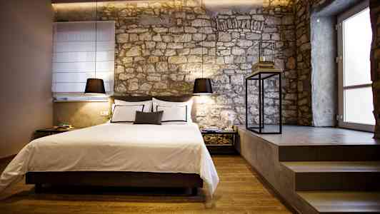 Tyylikäs makuuhuone, jossa on sänky ja kiviseinä. (Tekoälyn luoma teksti)