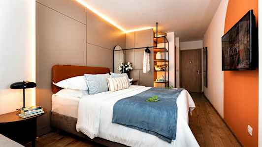 Moderni hotellihuone, jossa parivuode, koristeelliset tyynyt ja valaistus. (Tekoälyn luoma teksti)